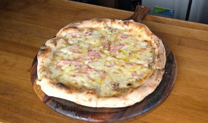 木製プレートに載ったCamps Pizzaのピザ