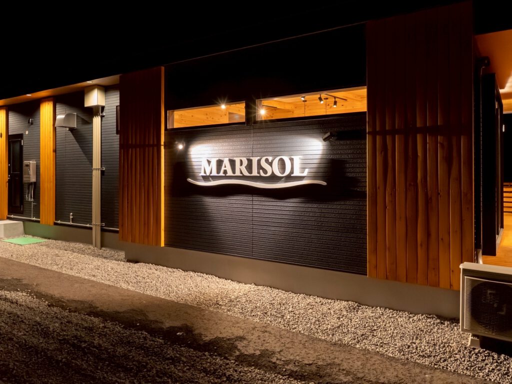 夜にライトアップされたMARISOL外壁ロゴ